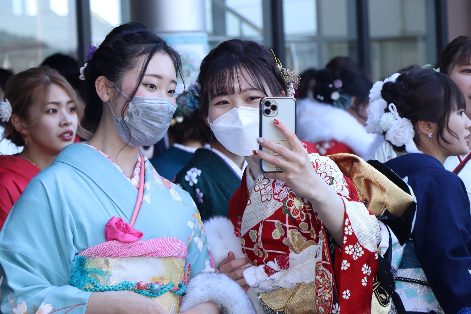スマートフォンで記念撮影しあう新成人方々の写真