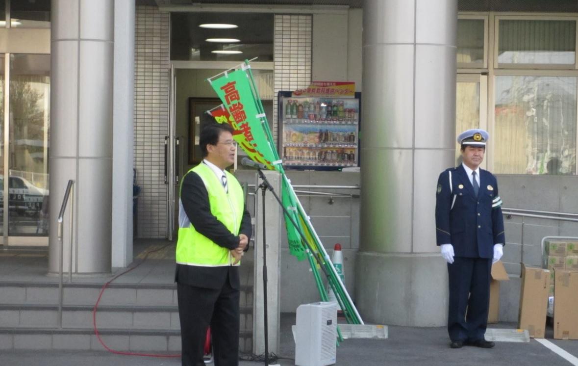 蛍光色のベストを身に着けた市長が交通安全の挨拶をする様子の写真