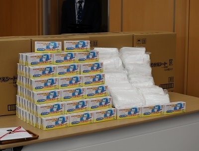 机の上にたくさん積まれた寄贈品のマスクと取り替えシートの写真