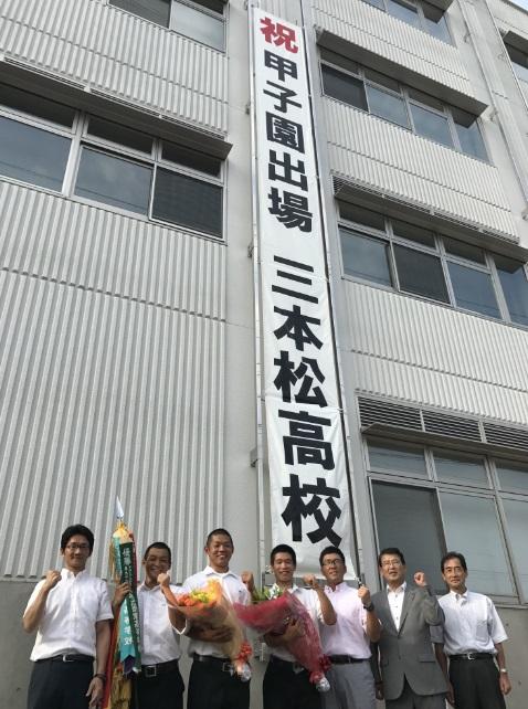 甲子園出場を祝う垂れ幕の前で市長と選手らの集合写真