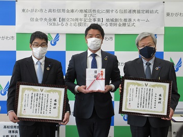 感謝状を持つ信金中央金庫四国支店長と高松信用金庫理事長、寄付金目録を持つ市長の写真