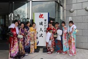 「東かがわ市成人式」とかかれた看板の前にて、笑顔でピースサインの振袖姿の新成人方々の集合写真