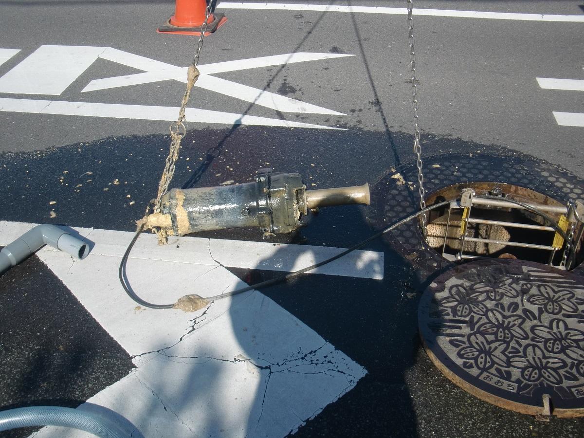 道路の排水からポンプに絡まった異物を取り除いている様子の写真