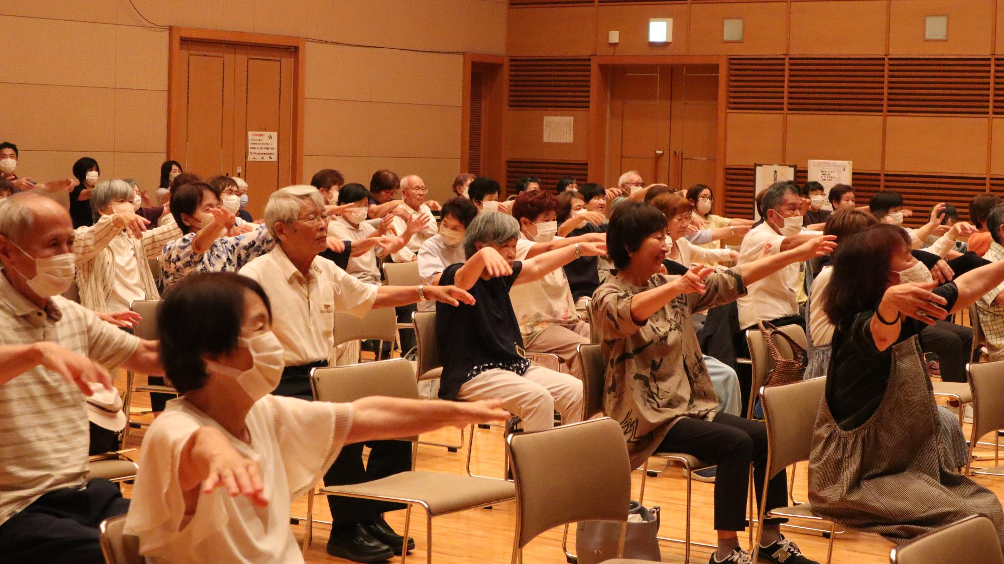 腕を前に上げて体操をする様子