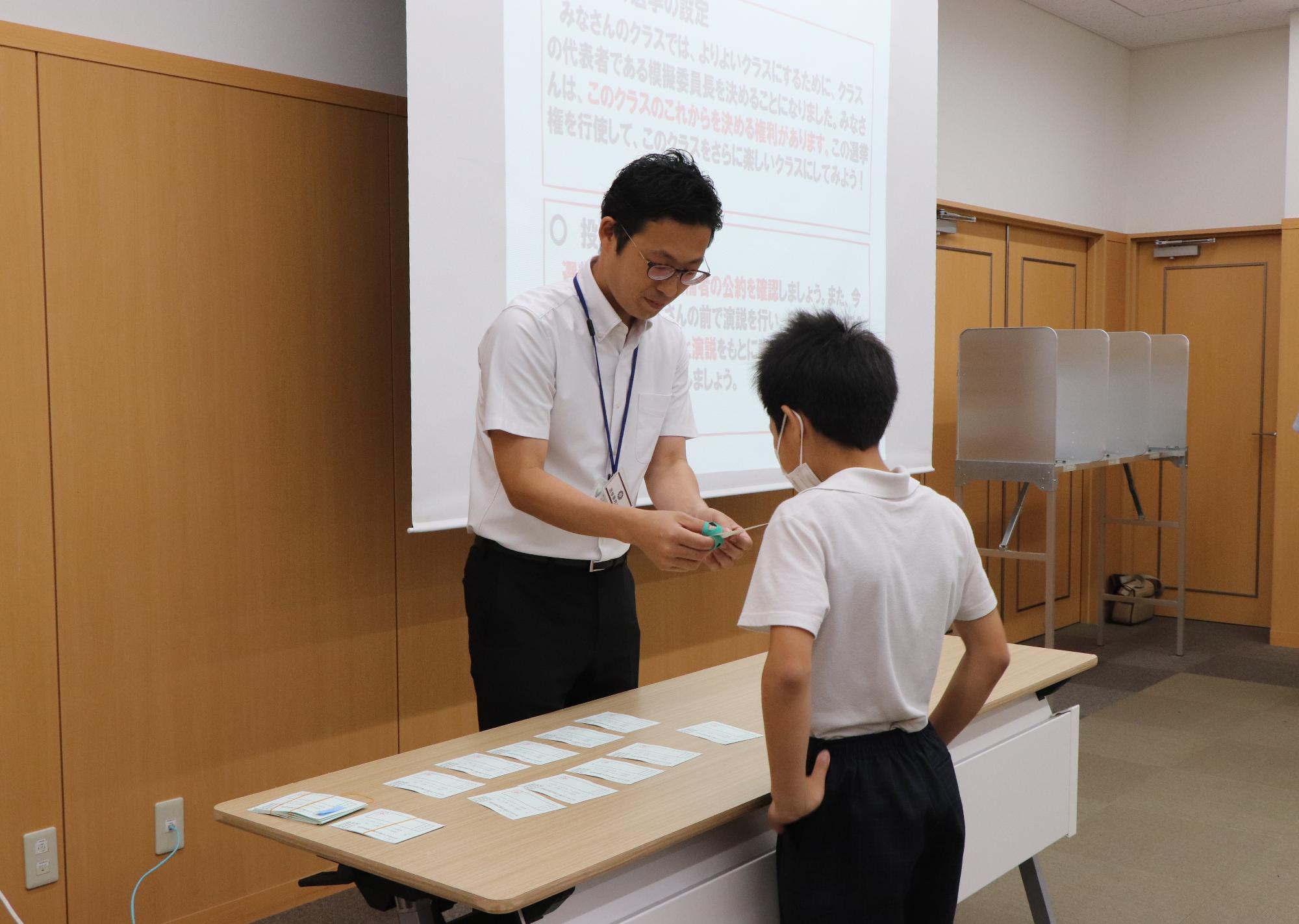 投票所や投票の流れについて説明を受ける児童