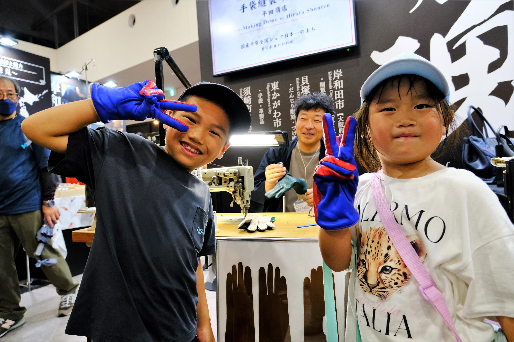 手袋縫製実演でつくった手袋をはく子どもたち