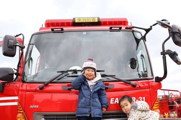 緊急車両の前でポーズを決める幼児らの写真