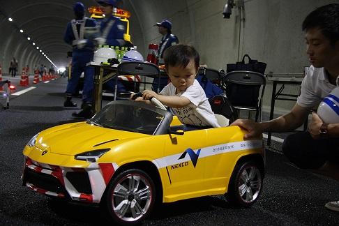 幼児がおもちゃのパトロールカーを運転している様子の写真