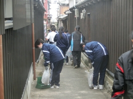 民家が並ぶ細い路地を清掃する中学生らの写真