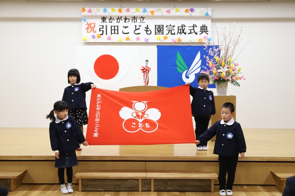 引田こども園完成式典で園旗を掲げる4人の園児の写真