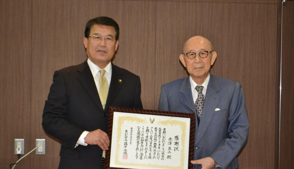 感謝状に手を添えた帝國製薬株式会社の社主赤澤庄三氏と市長の写真