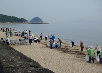 参加者らが浜辺で熱心に清掃している様子の写真