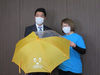 傘を持つ新居さんと市長の写真