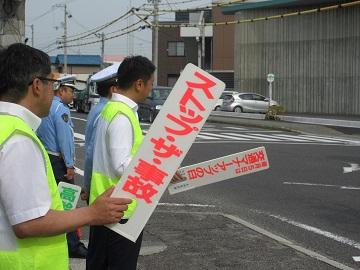 交通安全を呼び掛けた看板を持って立っている男性の写真