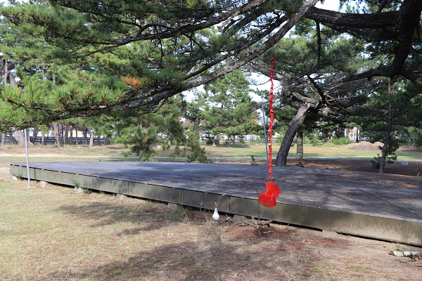 松の木から赤い紐のようなものをたらしたアートの写真