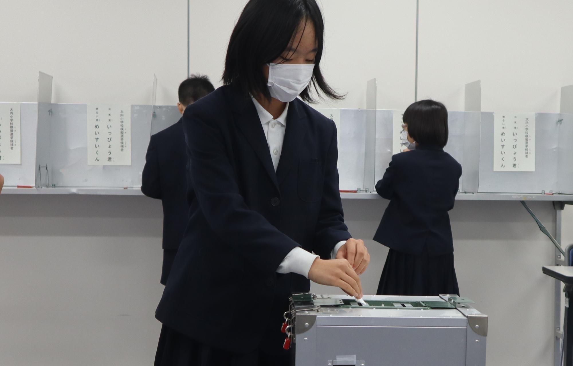 投票箱に投票用紙を入れる児童