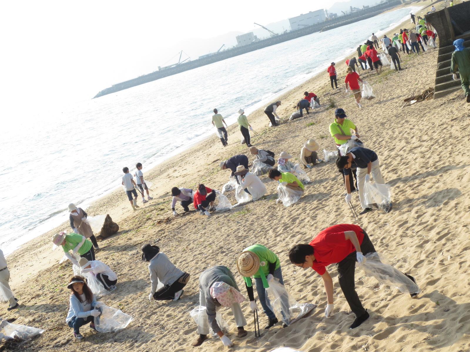清掃活動している参加者たちの背後に望む瀬戸内海の写真